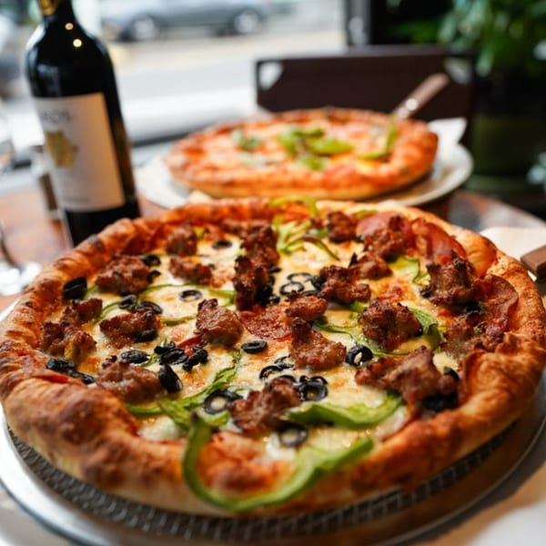 Olympia Pizza's sausage, olive, and green pepper pizza with a bottle of wine.