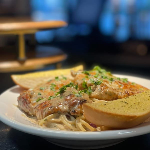 Chicken parmesan with spaghetti and garlic bread on a white plate at Olympia Pizza.