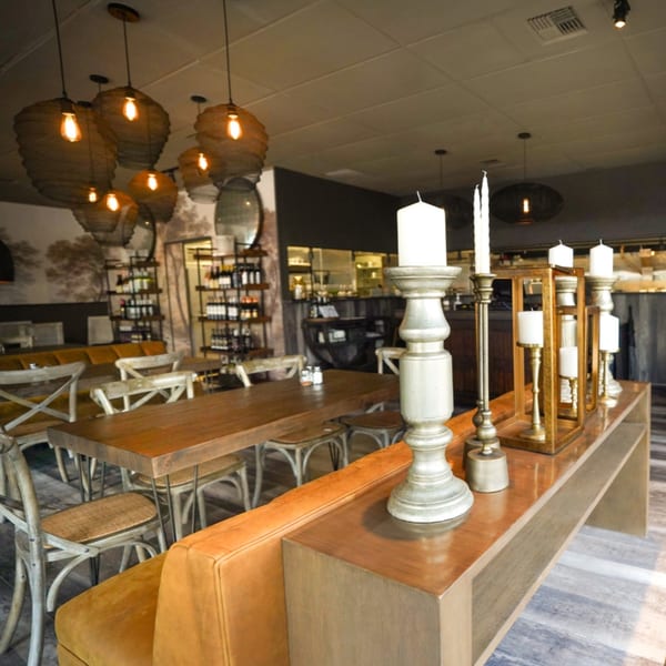 Warmly lit dining room at Olympia Pizza & Spaghetti House II with wooden tables, benches, and decorative candles.